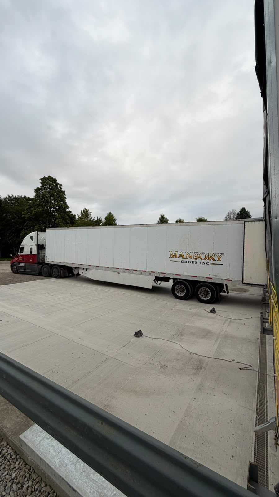 A Mansory Group truck and white trailer backed into a loading dock